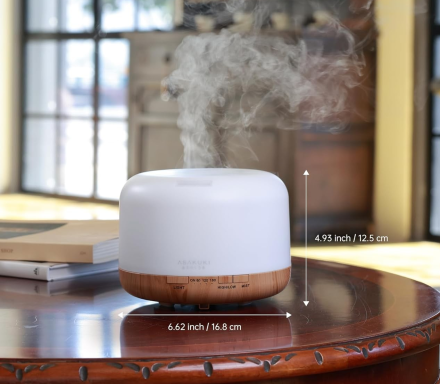 White and wood essential oil diffuser releasing vapor on a table.